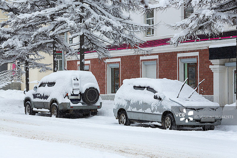 白雪覆盖的街道上的汽车。城市大雪的后果。图片素材