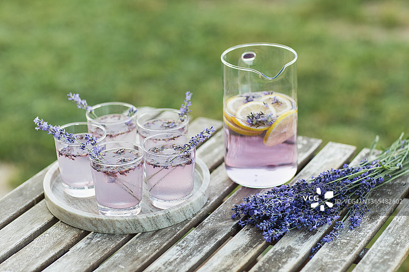 户外木桌上摆放着紫罗兰色的薰衣草花装饰鸡尾酒。图片素材