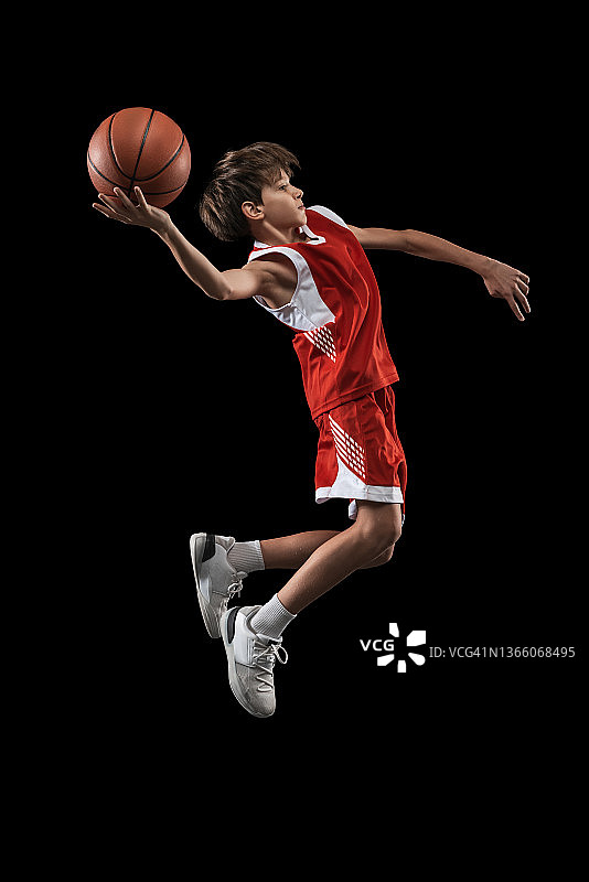 十几岁男孩的全身肖像，篮球运动员在运动，训练，在黑色背景下孤立地打球。侧视图图片素材