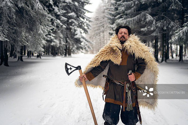 骄傲的中世纪武士，在冬天的森林里手持斧头图片素材