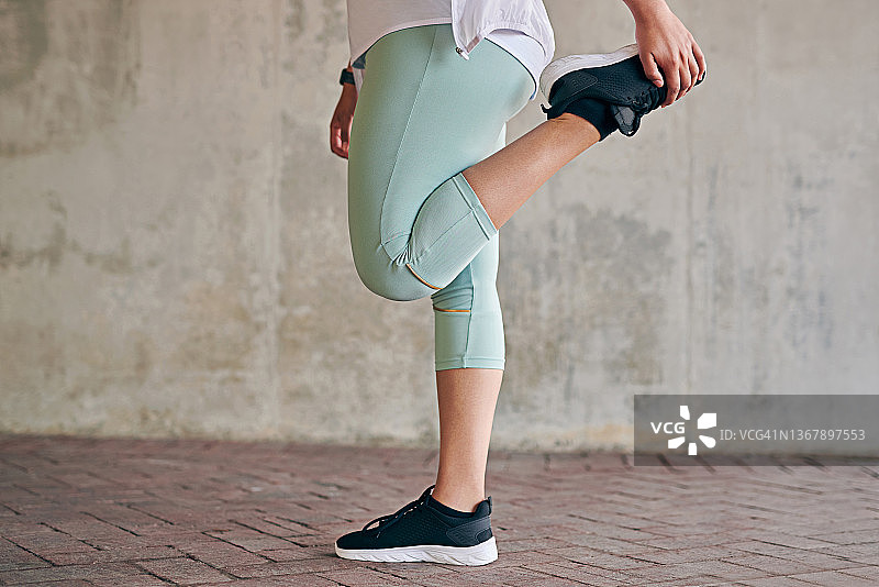 一名运动女性在户外锻炼时伸展腿的特写镜头图片素材