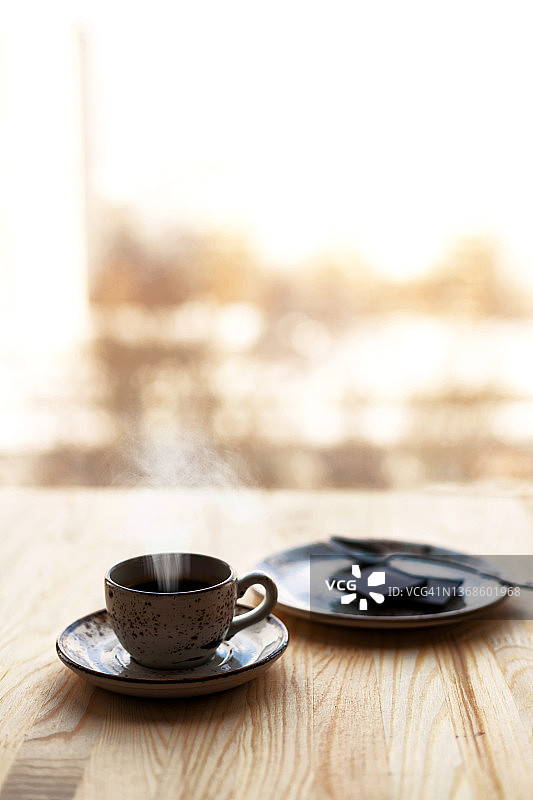 咖啡浓咖啡杯碟，黑巧克力盘，木桌，窗户模糊的城市背景图片素材