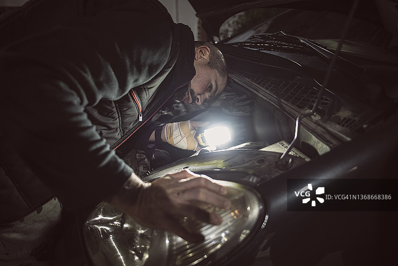 逼真的机械师在夜间紧急情况下修理汽车灯图片素材