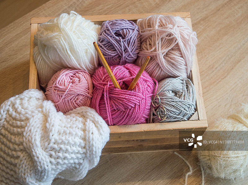 彩色羊毛球在一个木制的盒子与竹编织针图片素材