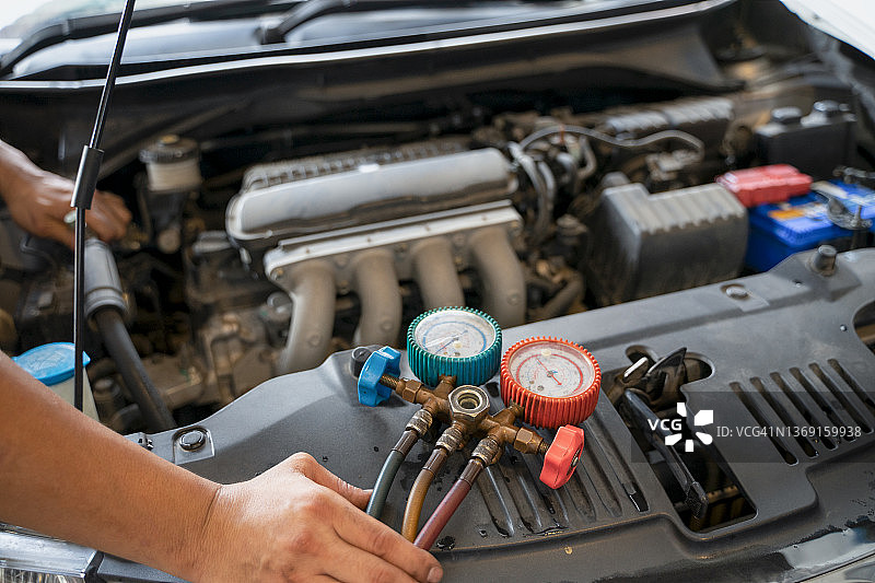 汽车空调检查服务，检漏，充注制冷剂。设备和仪表的液体冷却在汽车由专业技术人员。图片素材