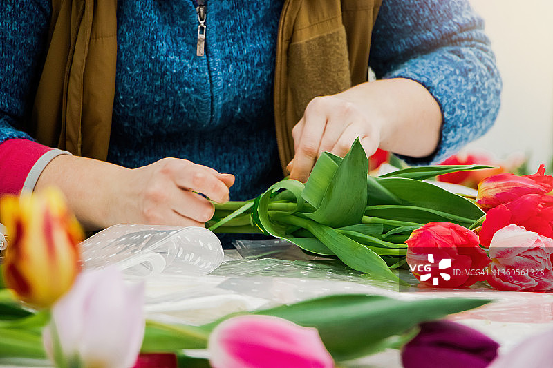 花商在花店制作郁金香花束。手捧五彩缤纷的春花。图片素材