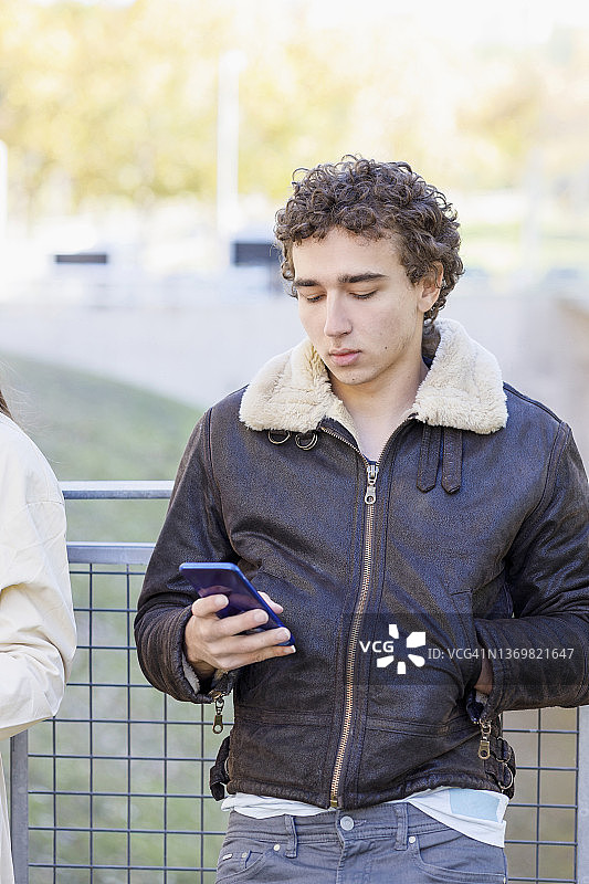 一个年轻人在栏杆前用智能手机图片素材