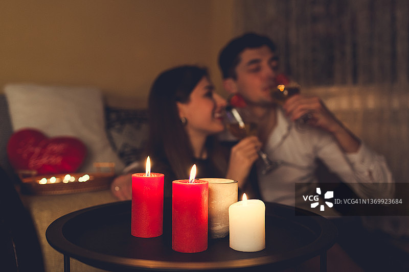 情人节，一对相爱的情侣喝着香槟，吃着草莓，在家里庆祝浪漫的晚餐图片素材