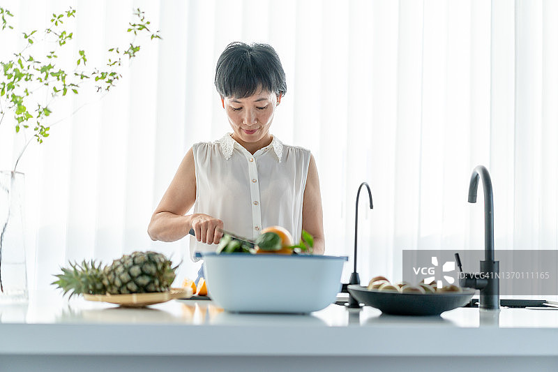 一位妇女在厨房切水果图片素材