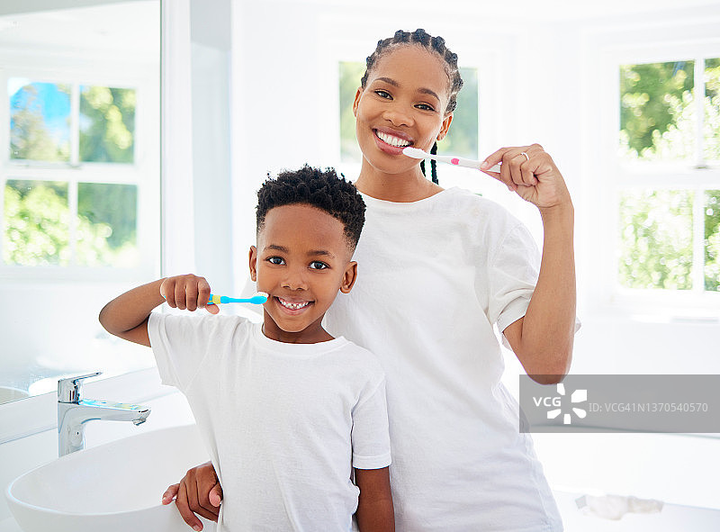 小男孩和他的妈妈在家里的浴室里一起刷牙的肖像图片素材