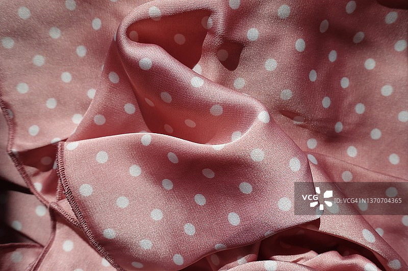 柔软的褶皱缎子织物与粉红色和白色的圆点图案图片素材