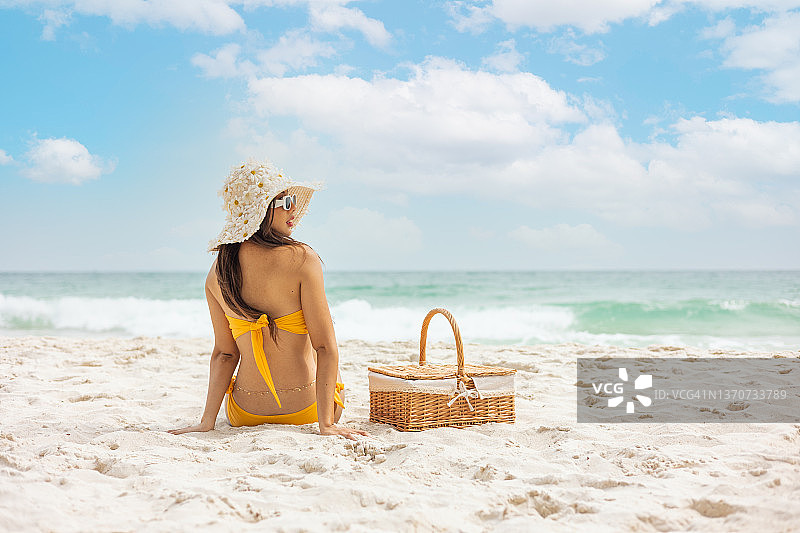 海滩假日妇女享受夏天的阳光坐在沙滩上看快乐的拷贝空间。年轻漂亮的比基尼模特。图片素材