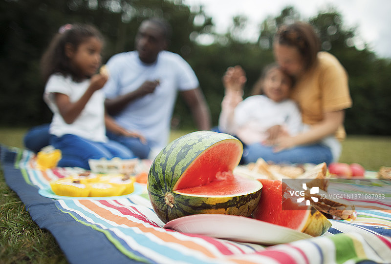 一家人在公园野餐毯上享受新鲜的西瓜图片素材