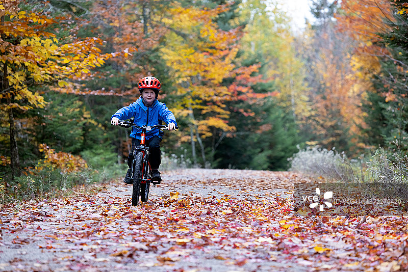 可爱的红发男孩在森林骑自行车在蒙特特伦布兰特国家公园，魁北克，加拿大秋天图片素材