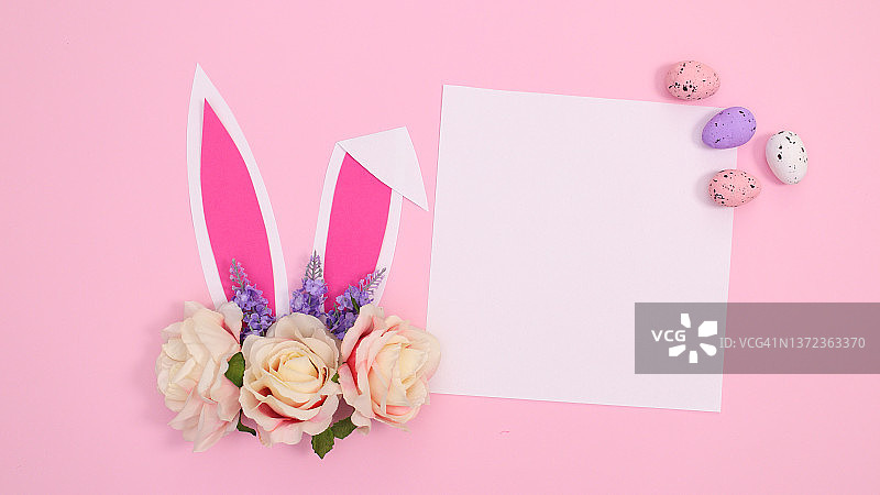 春节创意纸卡复制空间与兔子耳朵与鲜花在柔和的粉红色背景。复活节创意概念图片素材