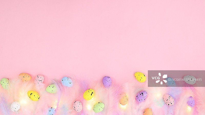 柔和柔和的时尚颜色羽毛在柔和明亮的粉红色背景与彩色鸡蛋。春天的概念。创意复制空间复活节平坦的奠定组成“n图片素材