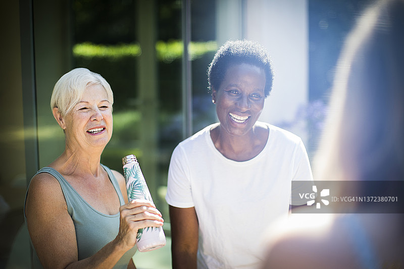 快乐的老年女性朋友在阳光明媚的夏日露台上大笑图片素材