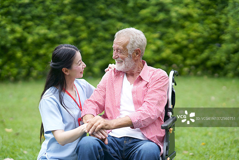 护士护理帮助老年男性轮椅上讨论愉快的后院图片素材
