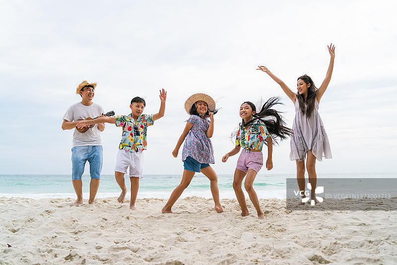 一群带着孩子的亚洲家庭在海滩上享受假期图片素材