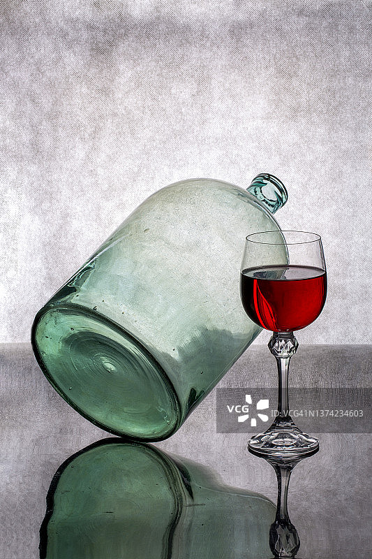 有一个倾斜的玻璃罐和一杯红酒的静物图片素材