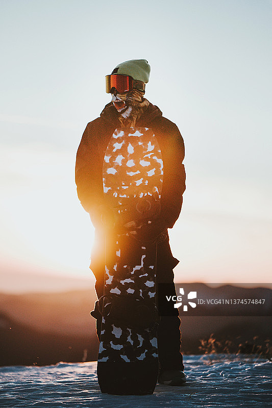 穿着运动服的滑雪板运动员和日落时在山上的滑雪板图片素材