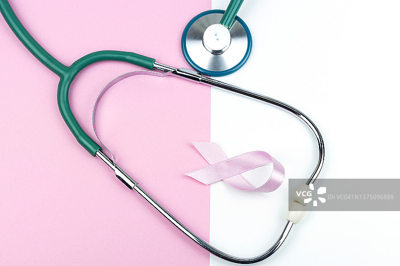 粉红色的缎带和听诊器与柔和的颜色背景。图片素材