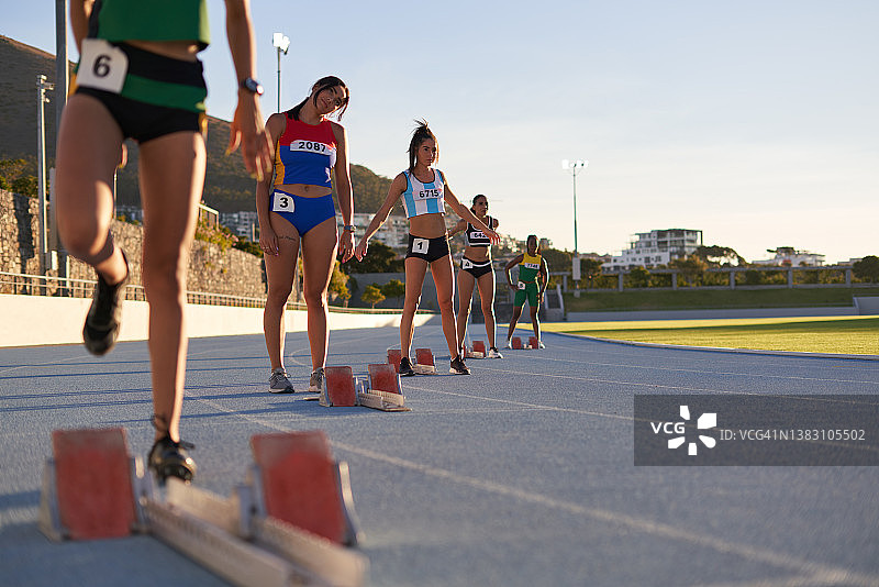 女子田径运动员在跑道上准备起跑图片素材