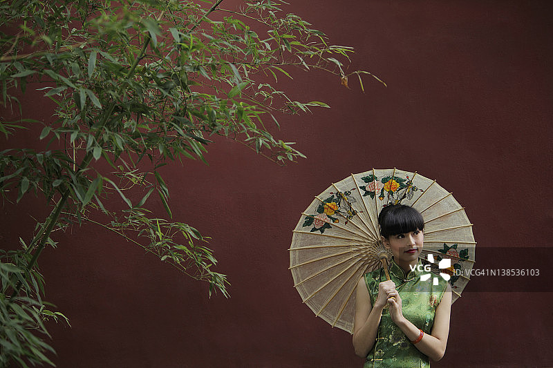 年轻女子穿着传统的中国服装，拿着伞图片素材