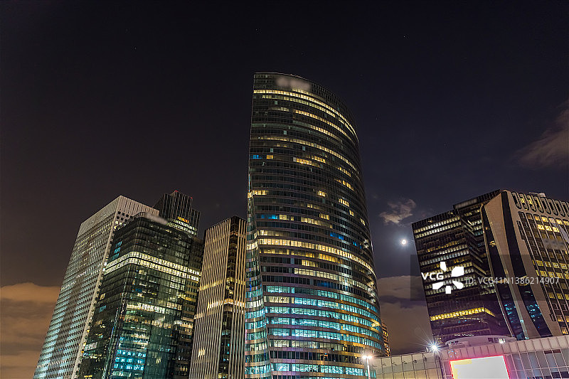 夜晚的月亮在拉德芳斯商业区的高楼之间穿行图片素材