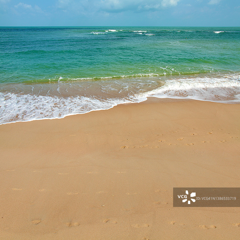 空旷的热带沙滩，阳光灿烂的日子里碧绿的大海图片素材
