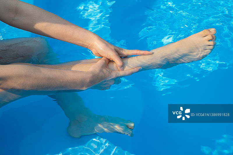 一个女人在游泳池游泳后腿部抽筋的特写。图片素材