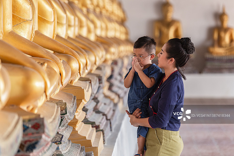 在泰国大城府普泰沙湾寺，母子正在为佛像祈祷图片素材