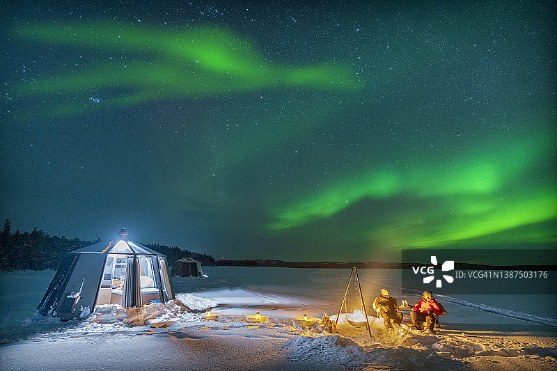 徒步旅行者坐在篝火旁享受北极光，拉普兰图片素材