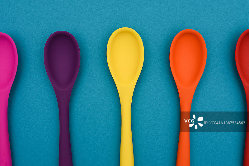 亮色的勺子在彩色的背景上。厨房的概念。图片素材