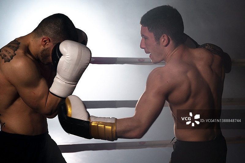 两个肌肉发达的年轻男性拳击手在拳击台上格斗。高质量的摄影。图片素材