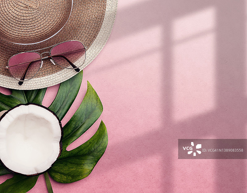 俯视图夏季组成与遮阳帽，太阳眼镜，椰子在粉红色的背景和复制空间图片素材