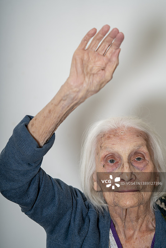 在家中举起手的年老女性的正面肖像图片素材