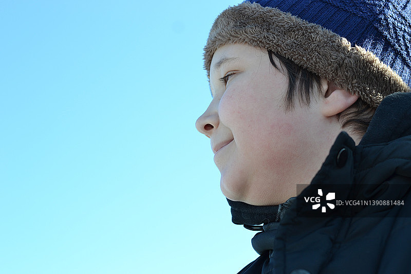 一个十几岁的男孩在蓝天下的肖像。图片素材