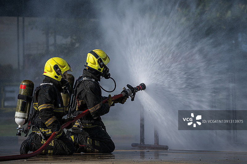消防队员喷高压水灭火，消防队员在紧急情况下用水和灭火器灭火。图片素材