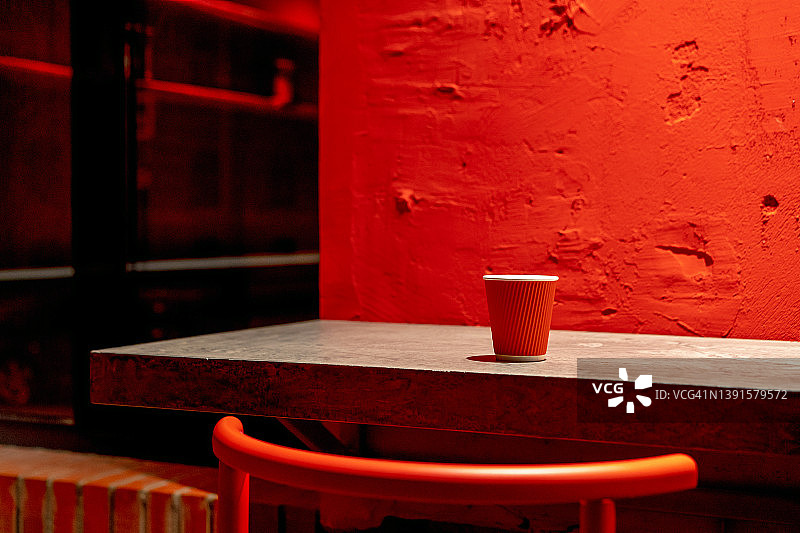一个红色的瓦楞纸一次性咖啡杯躺在灰色的混凝土桌子上，靠墙粉刷。外卖，咖啡外带。21、环境污染的概念，回收利用，再循环利用图片素材