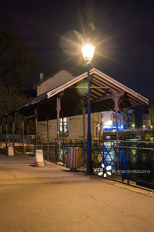 街道灯光和倾斜的屋顶旁边的河蒂欧在晚上-安纳西，法国图片素材