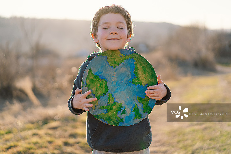 小男孩手里拿着星球，背景是绿色的春天图片素材