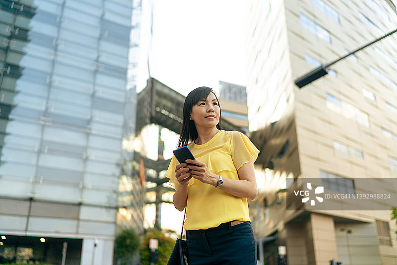 亚洲女性在城市背景下使用手机图片素材