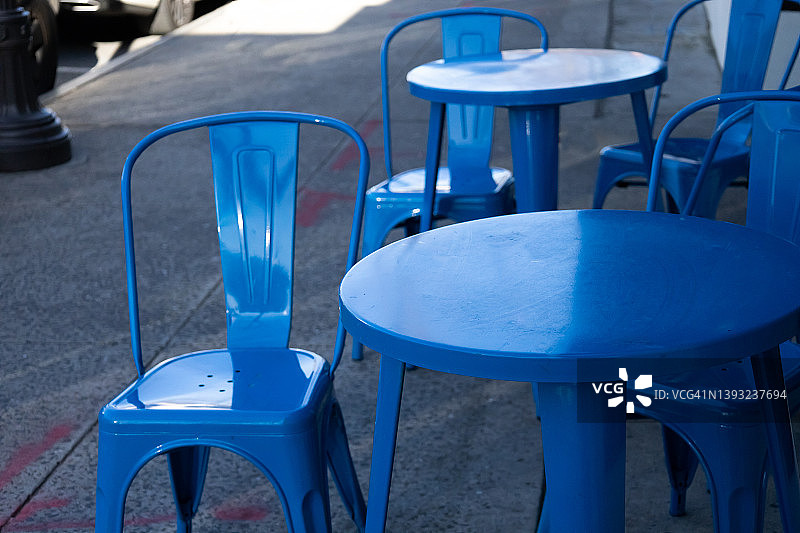 咖啡馆或餐厅的户外亮蓝色桌椅被推到人行道的一侧图片素材