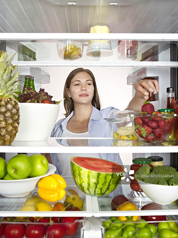 一位年轻女士在冰箱里翻看健康食品图片素材