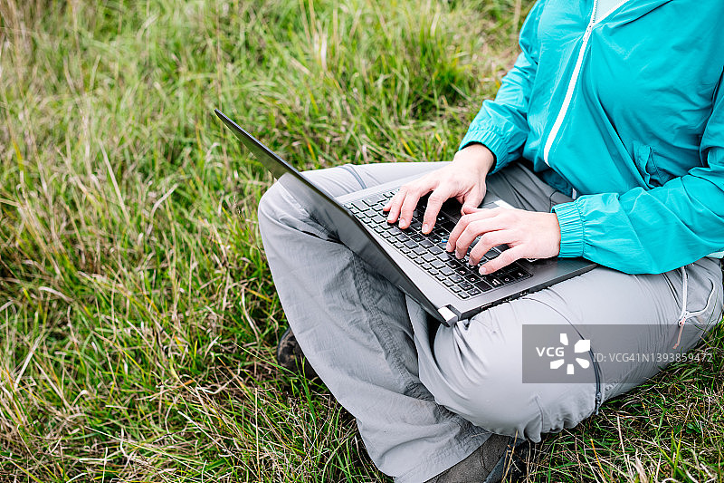 游牧妇女坐在草地上用她的笔记本电脑图片素材