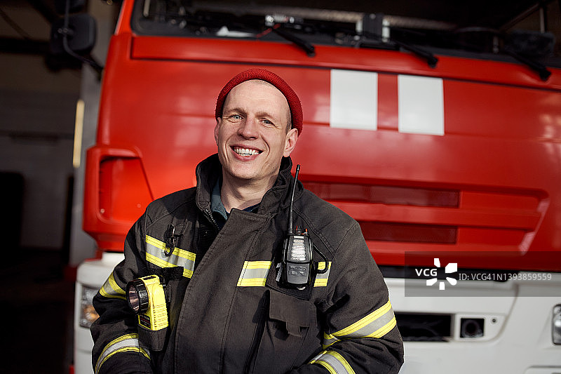 快乐的男消防员在卡车旁对着镜头微笑图片素材