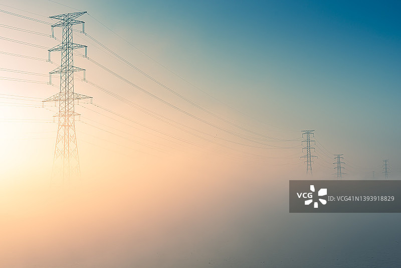 清晨，高压电塔从雾中隐约可见图片素材
