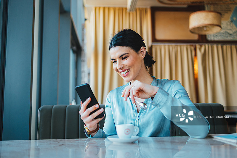 一位女商人一边喝咖啡休息一边发短信图片素材