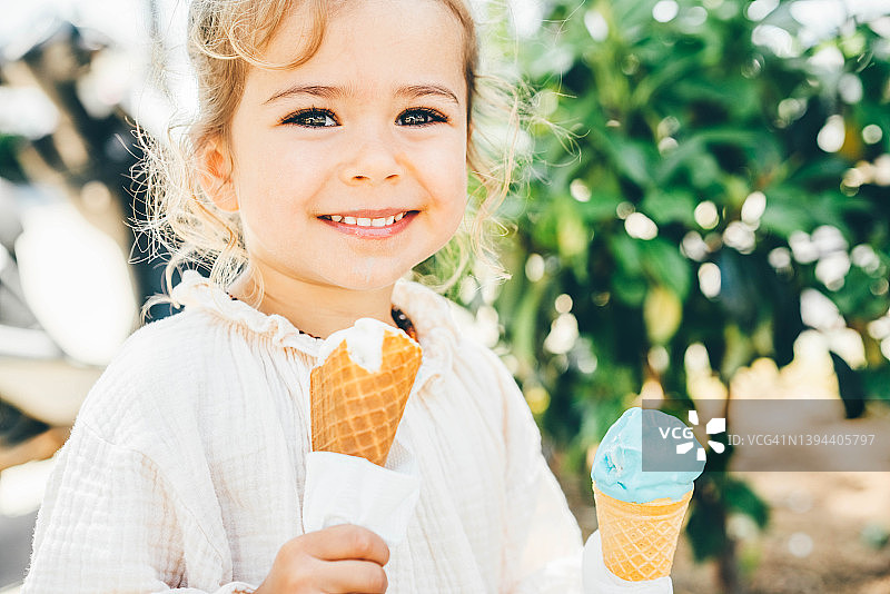 可爱的小女孩在户外吃冰淇淋的肖像。图片素材